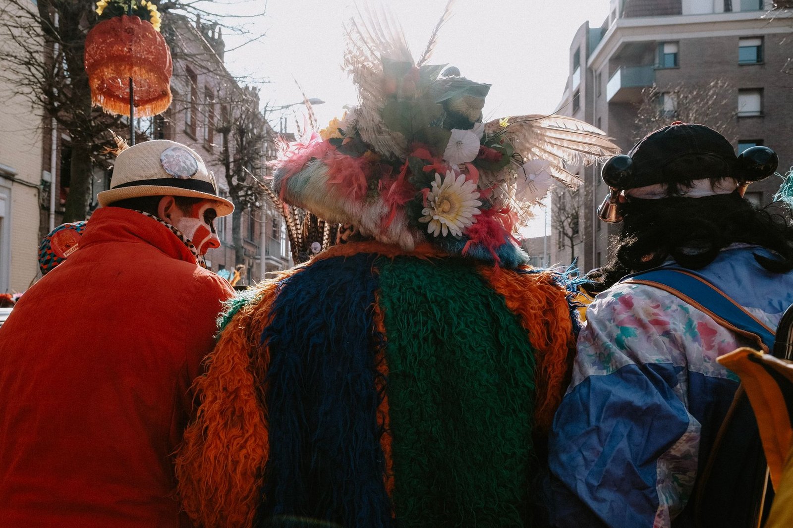 Grupo de personas disfrazadas con máscaras y plumas en un desfile de carnaval en la calle