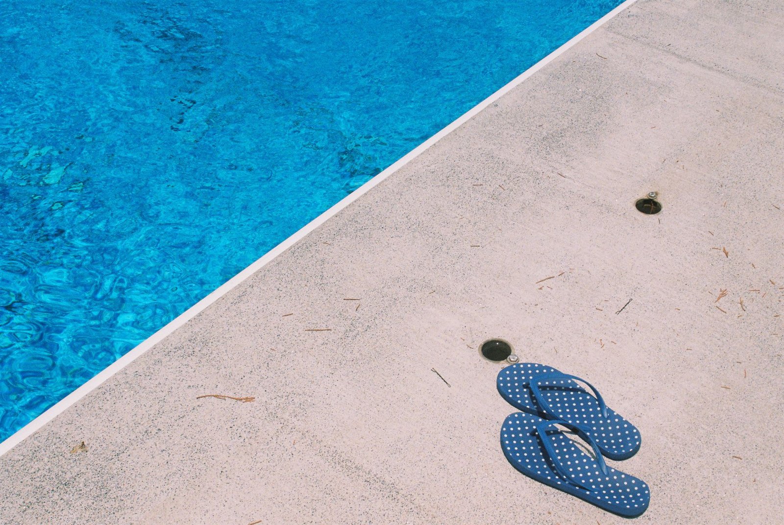 Chanclas junto al borde de una piscina en verano