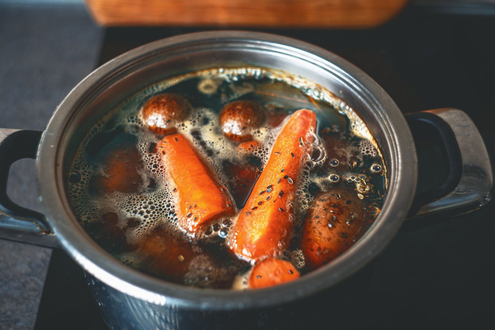 Olla con caldo casero recién hecho junto a verduras troceadas sobre la mesa