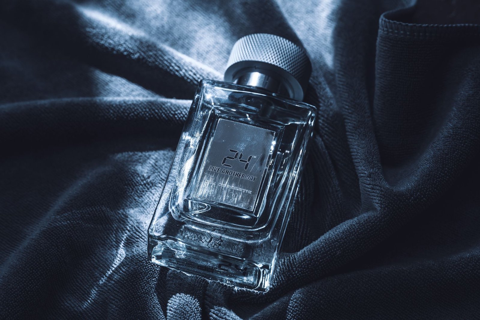 Frasco de perfume masculino sobre una superficie clara junto a hojas verdes