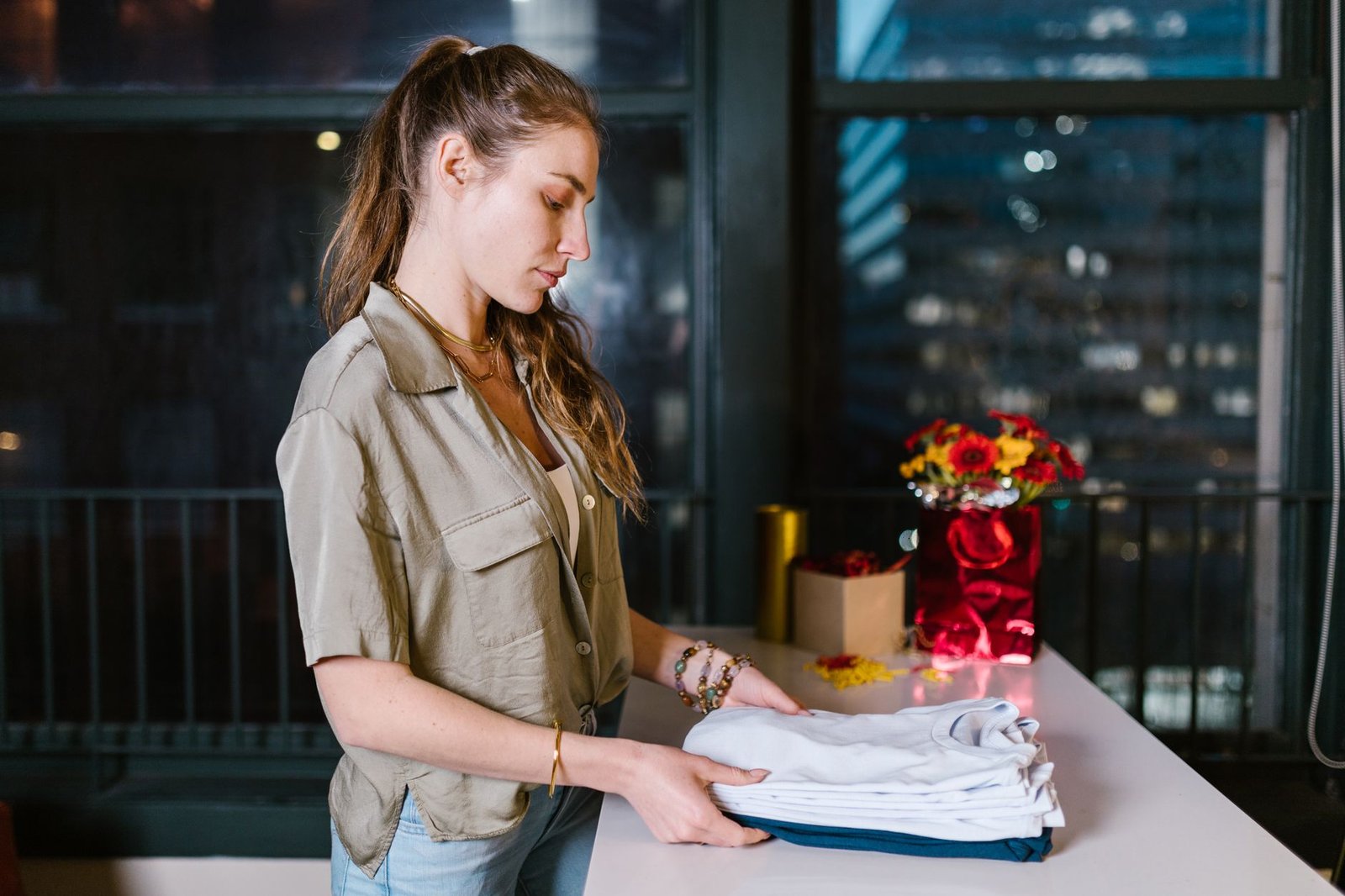 Mujer doblando un jersey junto a una caja de regalo abierta