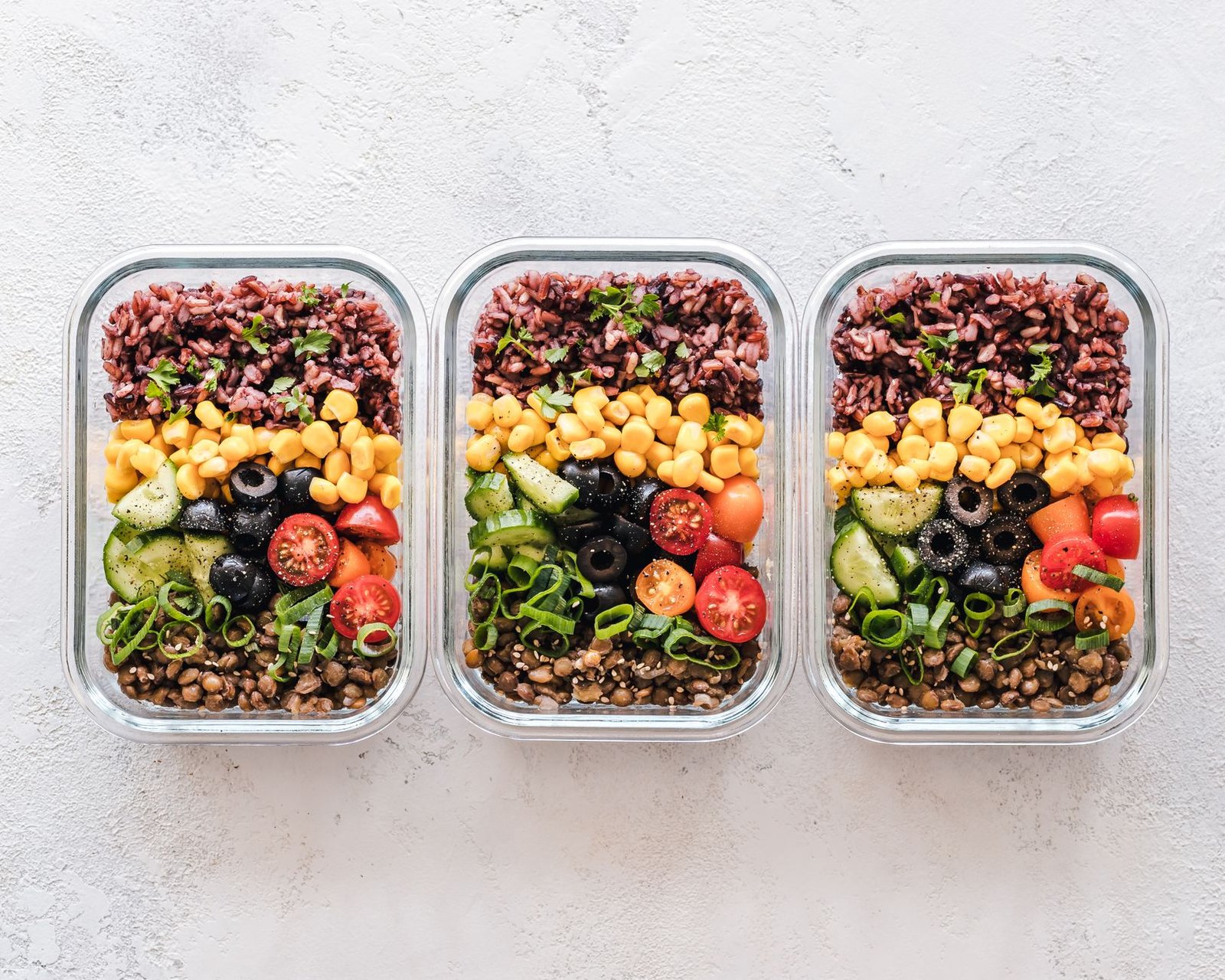 Recipientes de cristal con verduras asadas, legumbres y cereales preparados para la semana
