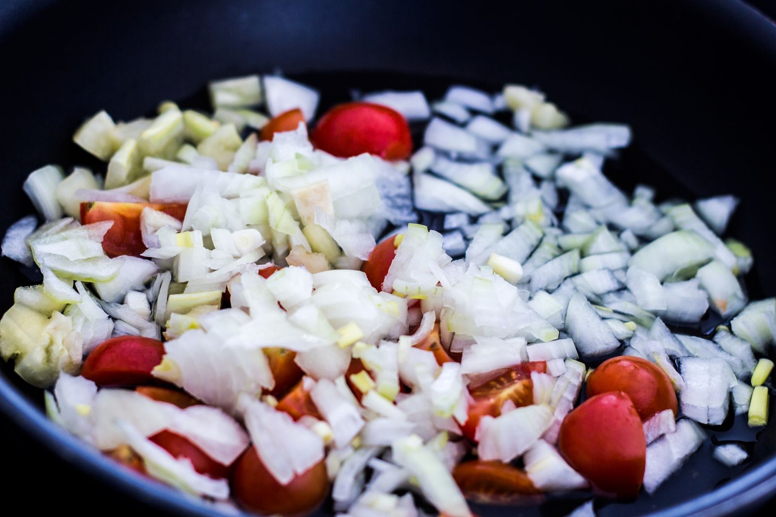 Cazuela con cebolla y tomate cocinándose lentamente para hacer un sofrito