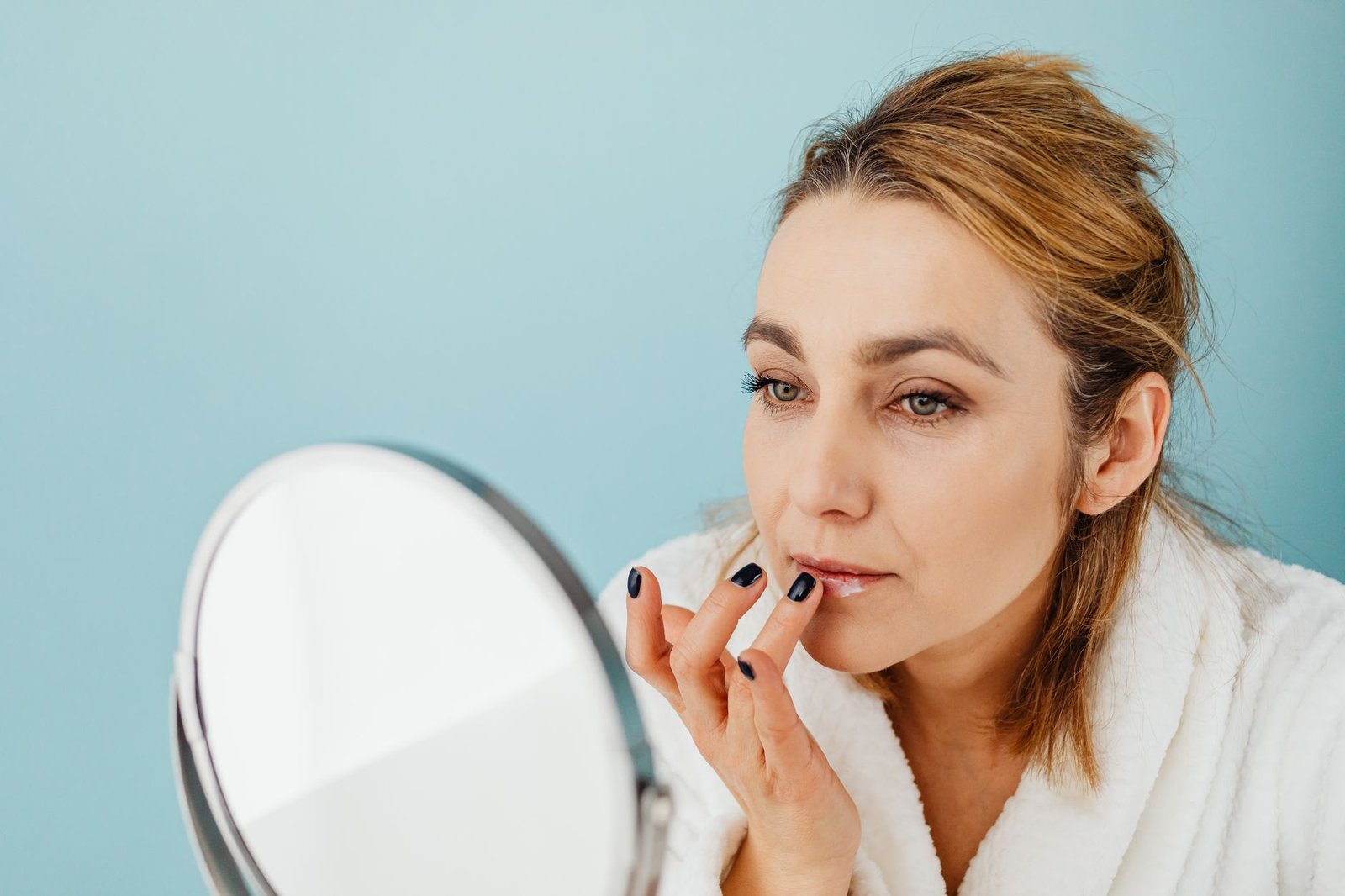 Mujer aplicándose bálsamo en los labios en un día frío