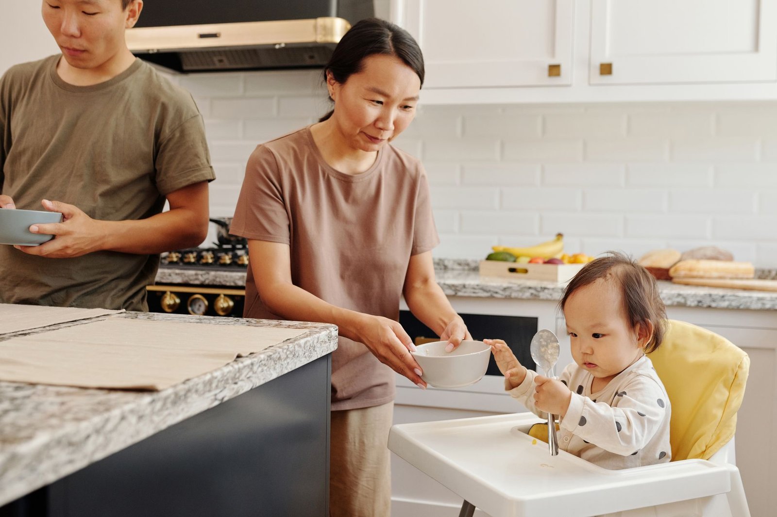 Una pareja hablando en la cocina mientras su hija pequeña está sentada a la mesa